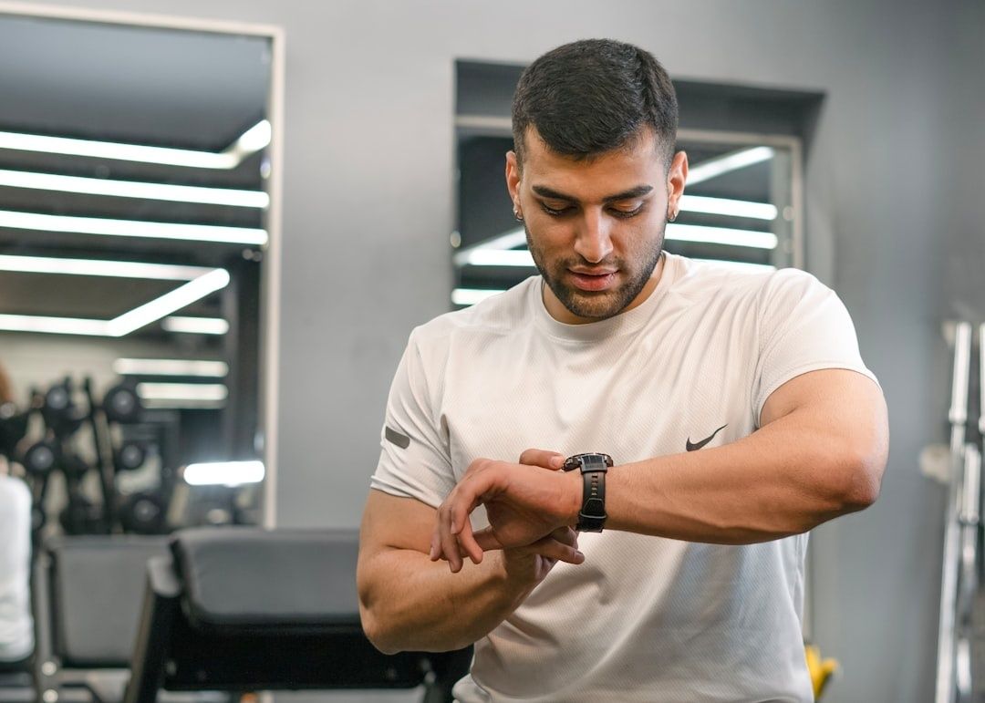Man i träningskläder kontrollerar sin sportklocka på gymmet