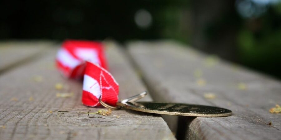 En medalj med rött och vitt band ligger på en träbänk